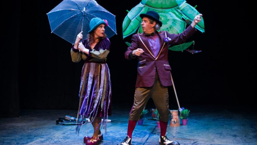 imagen de los dos actores en escena con paraguas abiertos 