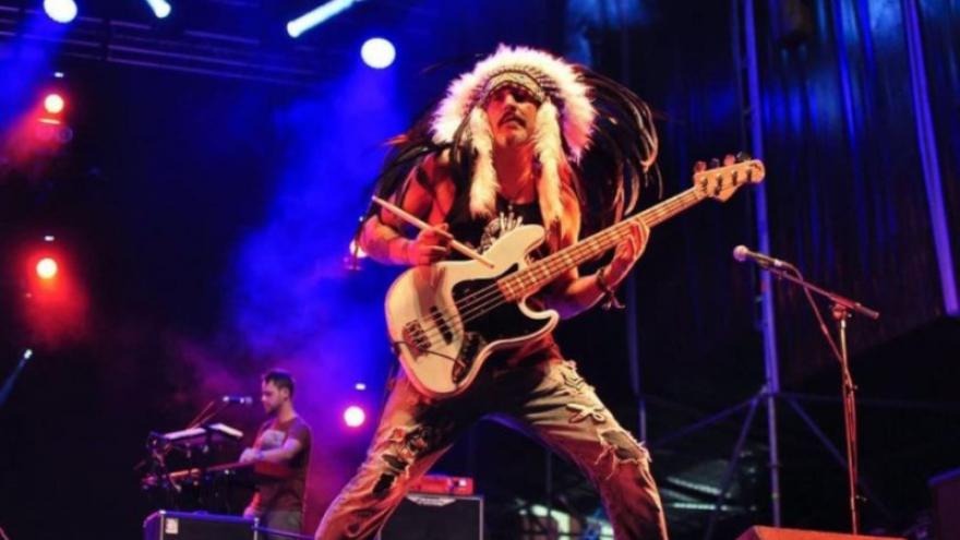 imagen Pepe Bao tocando el bajo en un concierto, lleva un tocado de plumas indio 