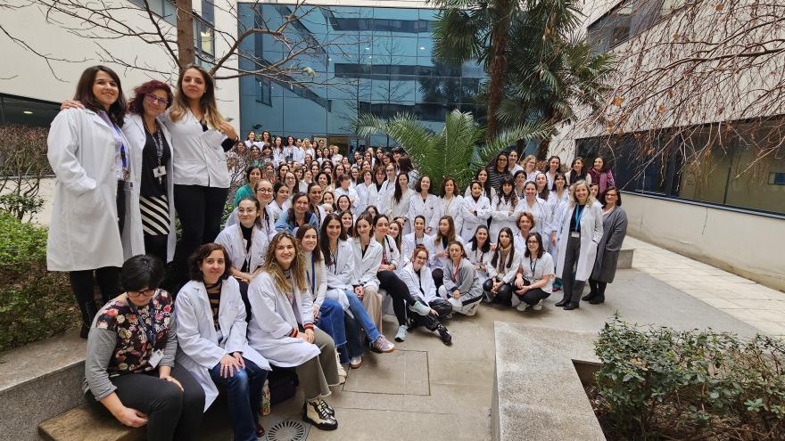 muchas mujeres posando con bata blanca en un jardín