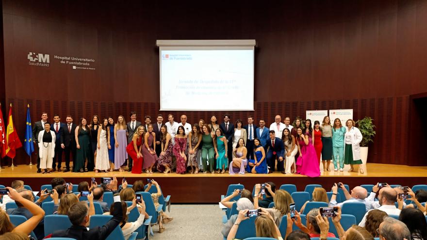 Personas de pie y personas sentadas en un salón de actos