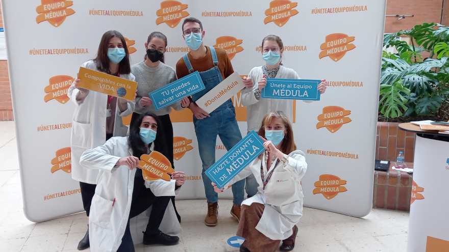 Grupo de alumnos posando con profesionales y carteles de promoción de la donación de médula