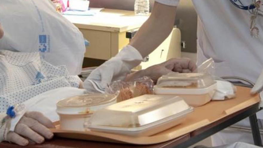 Personal sanitario entregando una bandeja de comida a un paciente