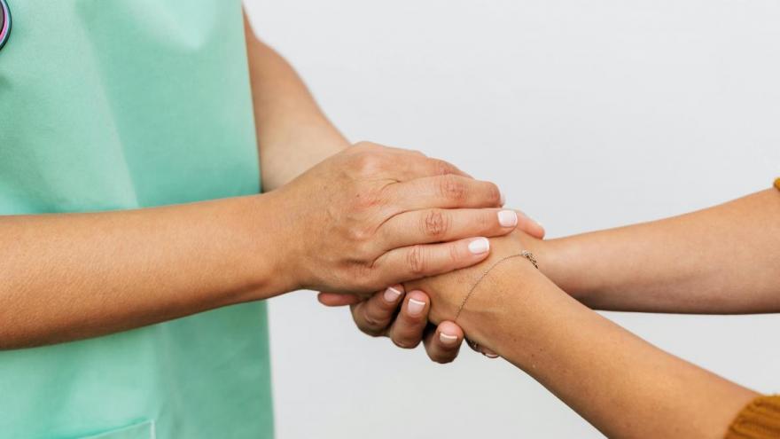 Imagen de un profesional sanitario cogiendo de la mano a una persona