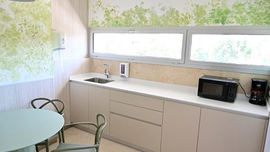 Sala equipada con un mesa y sillas y un office de cocina con nevera y microondas