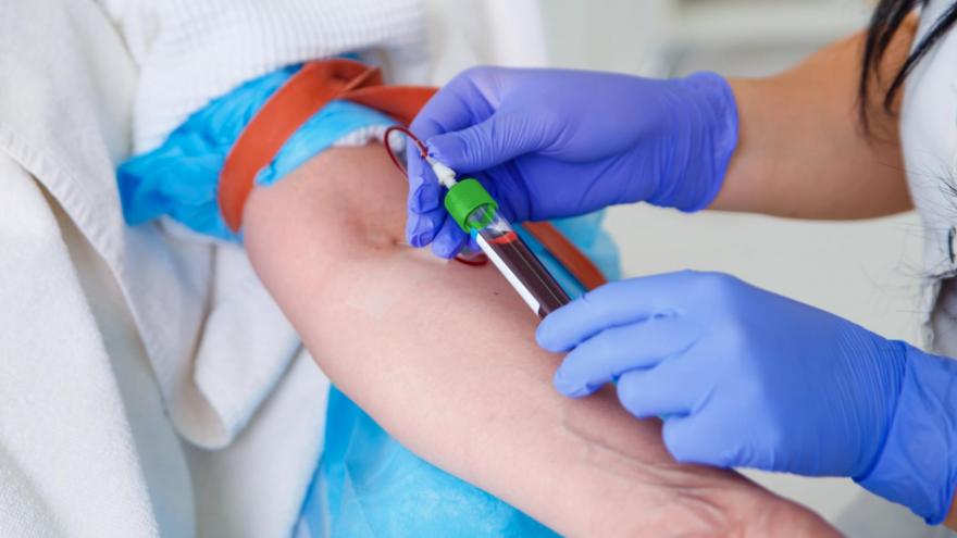 Unas manos de sanitario extrayendo tubo de sangre de un brazo