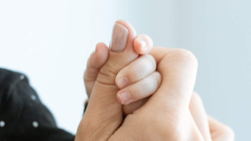 Imagen de un pulgar de mano de adulto agarrado por una mano de bebé