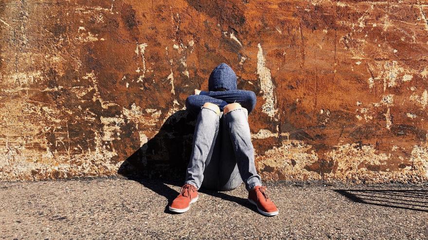 Joven triste sentado en el suelo en la calle