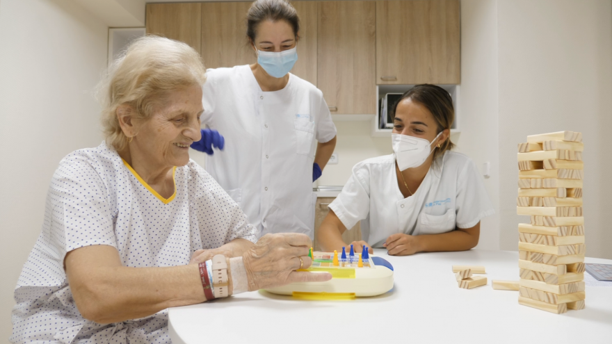 Una persona mayor junto a enfermeras en una sala de estar