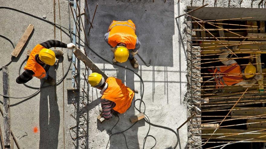 Obreros de la construcción en lo alto de un edificio al sol