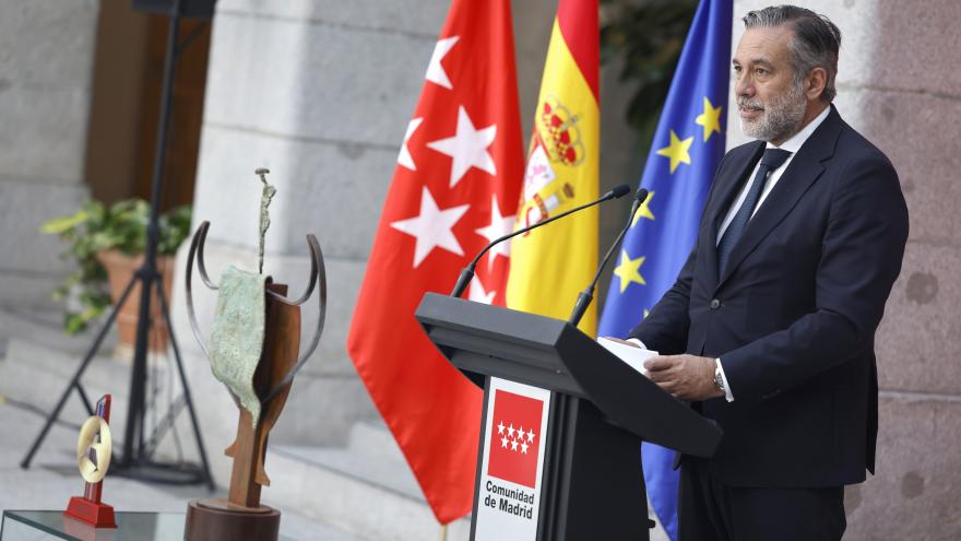 El consejero Enrique López interviene en el acto desde el atril con el trofeo al lado