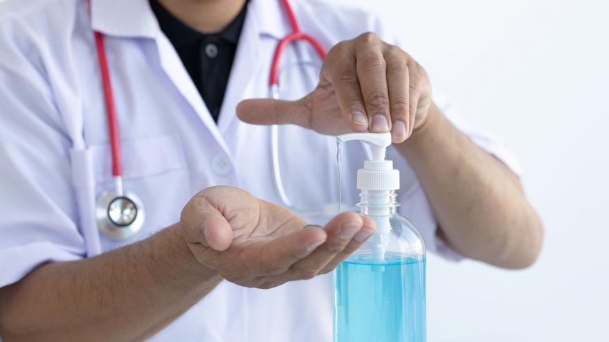 Médico con fonendoscopio aplicándose gel hidroalcohólico en sus dos manos