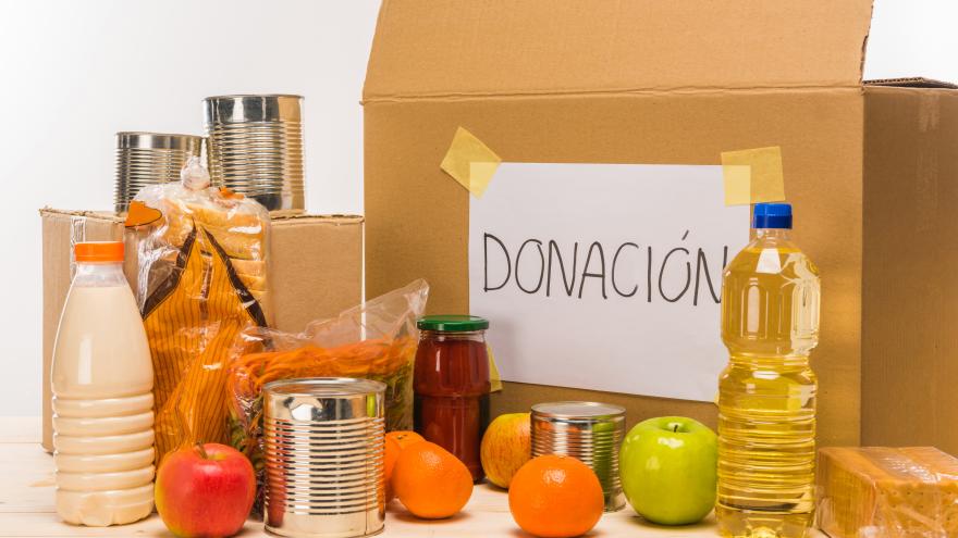 Caja con un cartel donde se lee "donación junto a diferentes alimentos