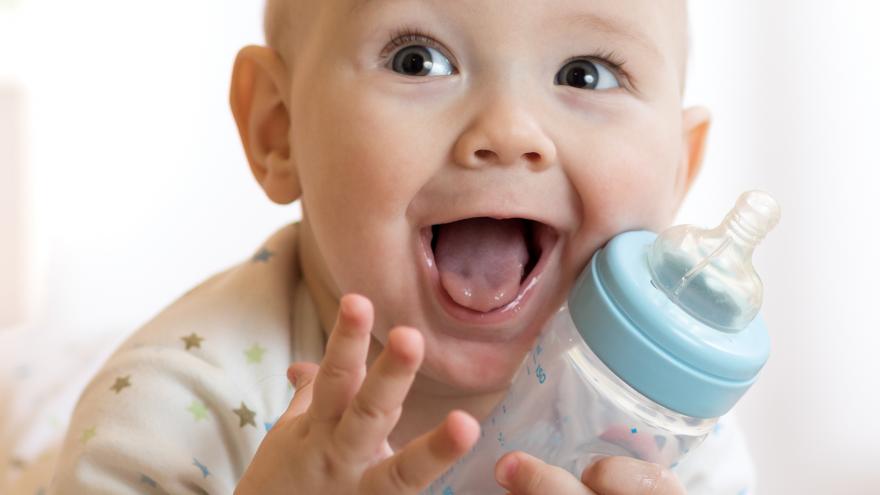 Bebé sonriendo con un biberón en la mano