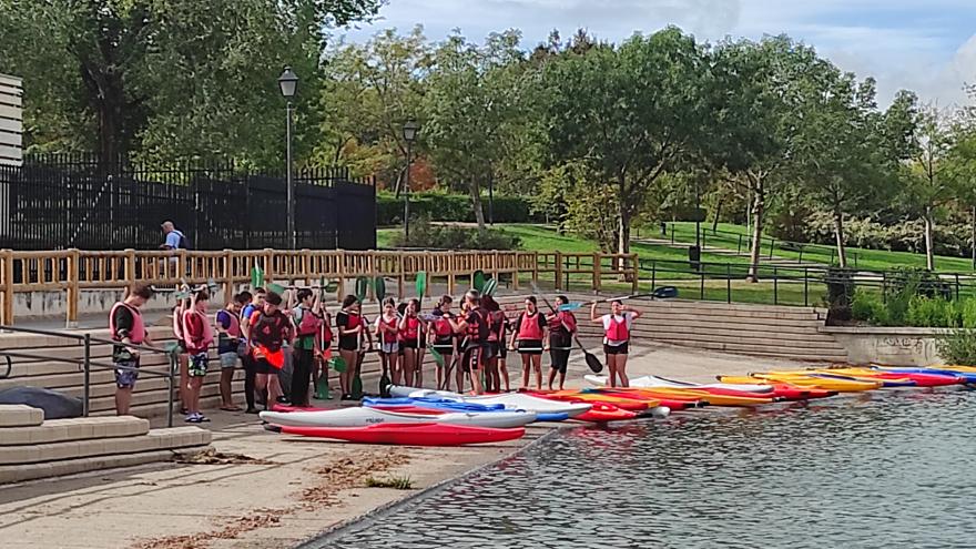 Jóvenes preparados con las piraguas en la orilla del lago