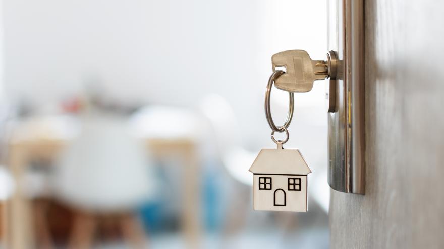 Llave colgando de una puerta con un llavero de una casa