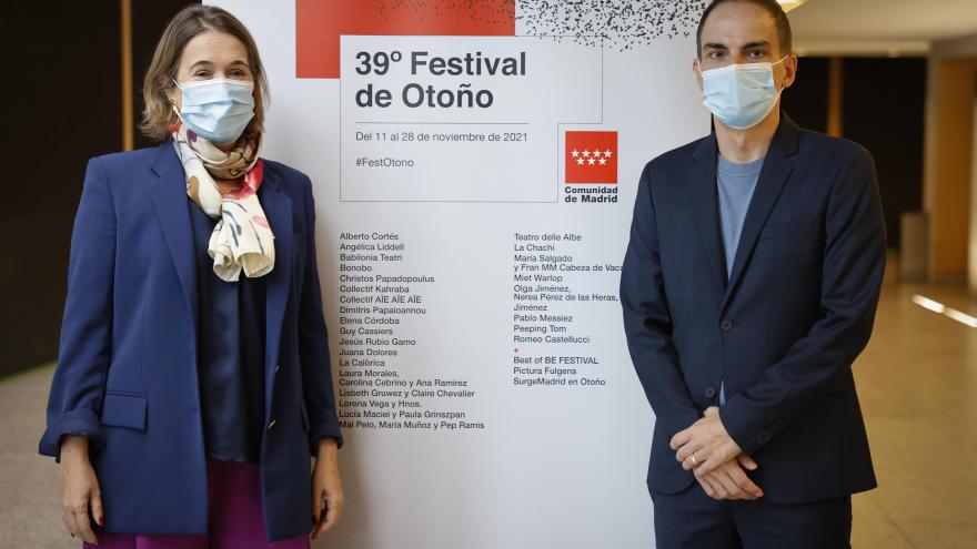 Dos personas posan con el cartel de actuaciones del festival de otoño