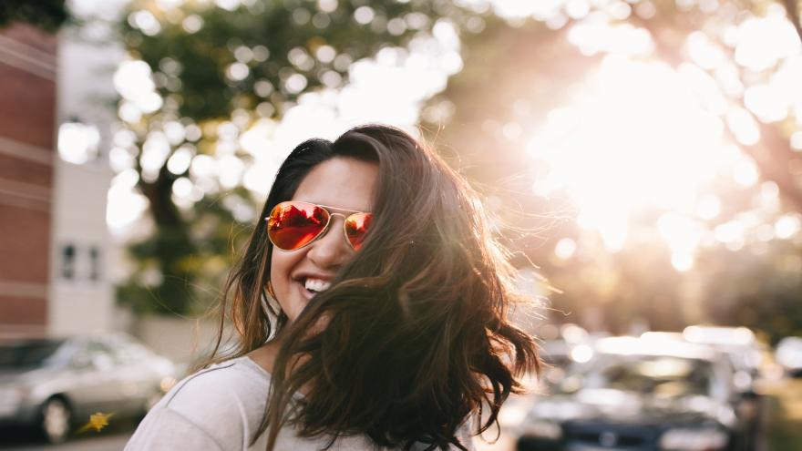 Chica con gafas de sol y pelo suelto sonriendo