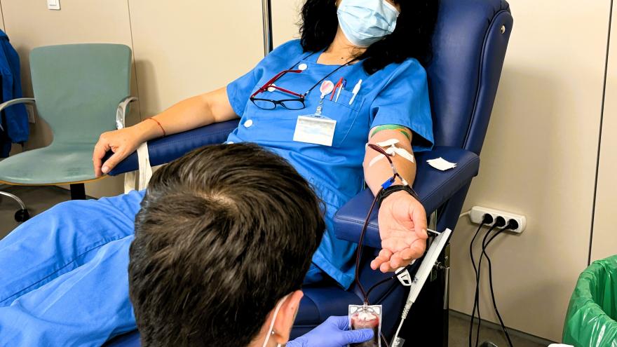 Una persona sentada en un sillón dona sangre