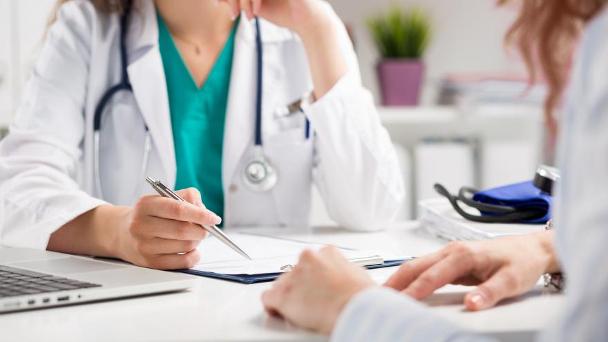 Una doctora atendiendo en consulta a un paciente