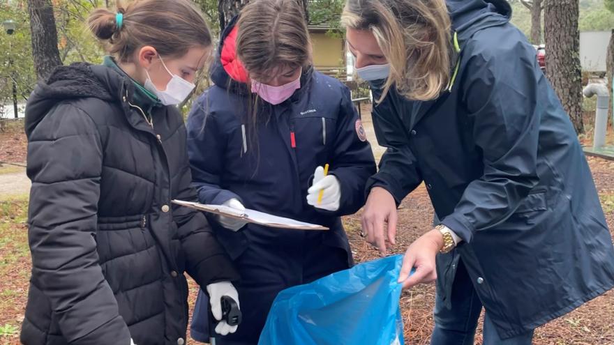 La consejera, junto a dos niñas, revisan los residuos de una bolsa azul