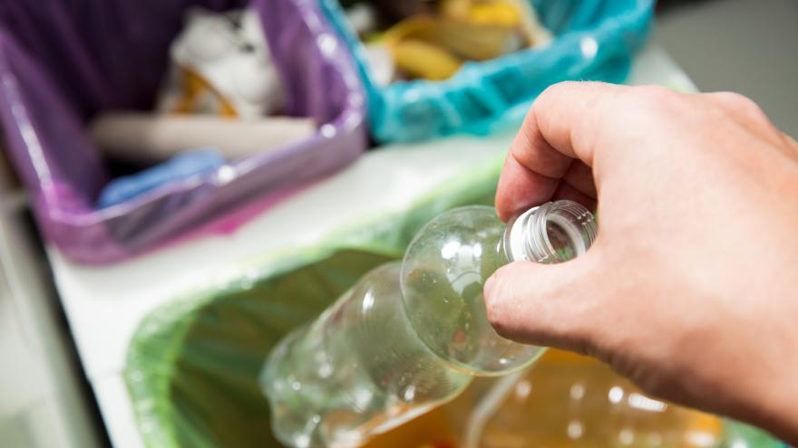 Una mano tirando una botella de plástico