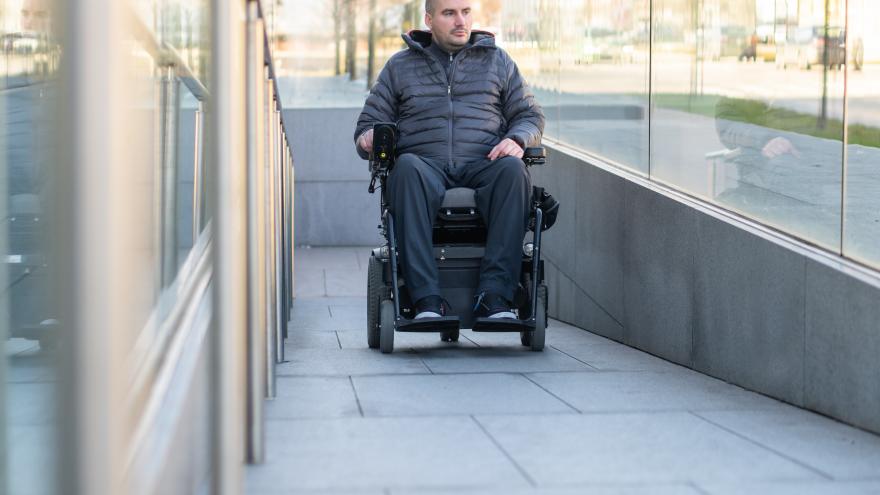 Hombre subiendo rampa en silla de ruedas eléctrica