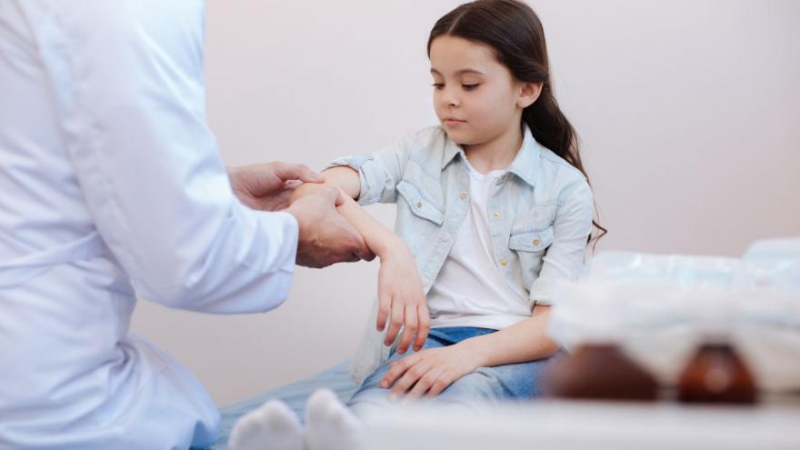 manos de médica que toca manos de niña