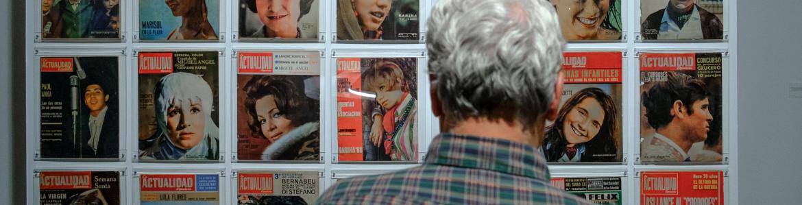 Man looking at magazine cover posted on a wall