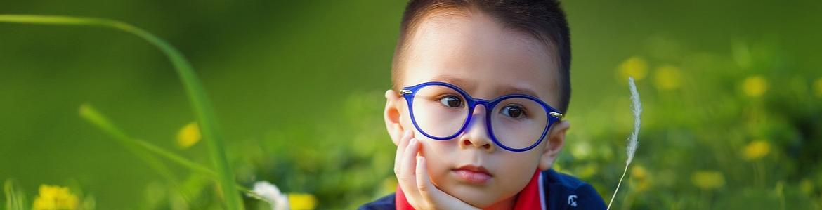 Niño con unas gafas puestas de colora azul, en el campo