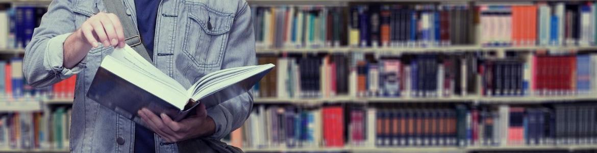 Persona en una biblioteca sosteniendo un libro