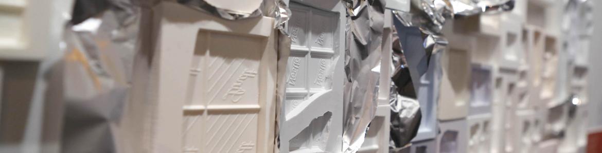 Placas de moldes de chocolates en distintos materiales plásticos y pegadas unas a otras como un panel en la parez