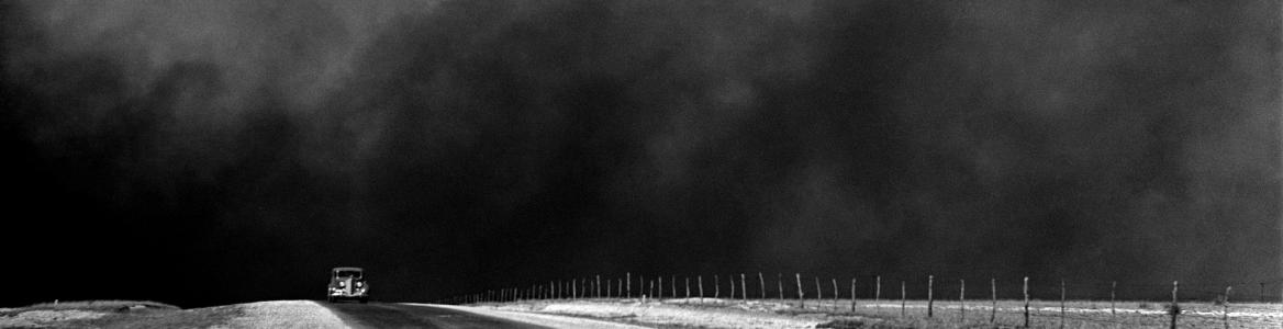 Imagen en blanco y negro de una carretera con un coche y el cielo lleno de polvo