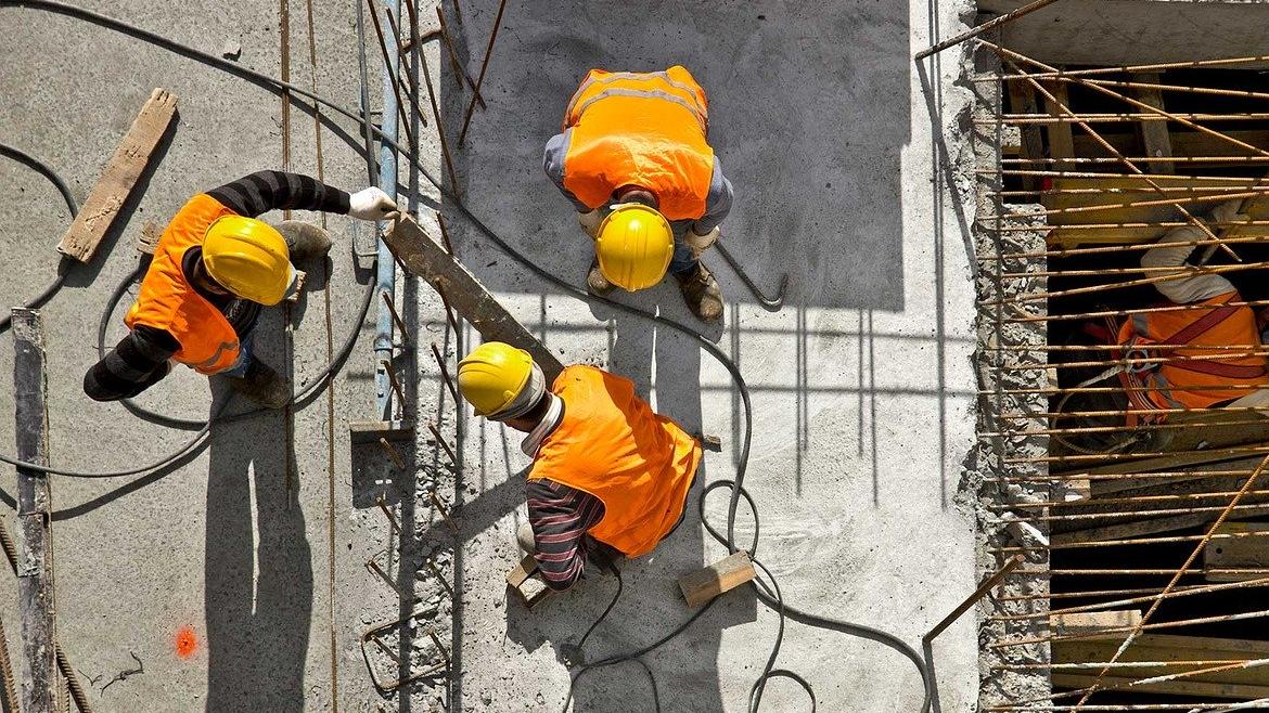 Obreros de la construcción en lo alto de un edificio al sol