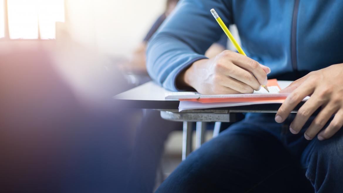 Un estudiante escribe sentado en su escritorio