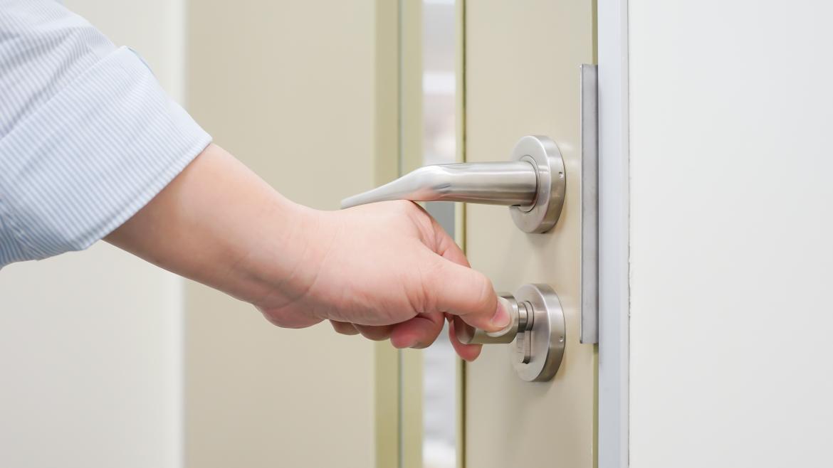 Una mano abre con una llave la puerta de una vivienda