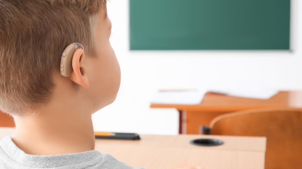 Un niño con un audífono en clase