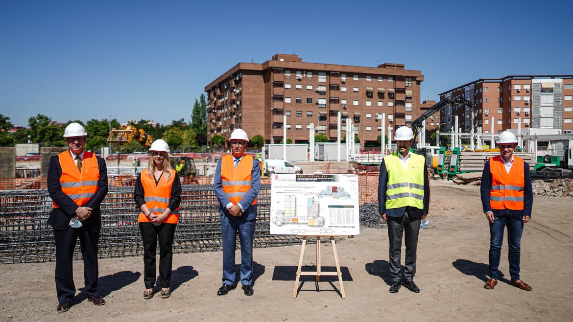 El consejero junto con el resto de miembros posan en las obras del nuevo colegio junto al plano del mismo