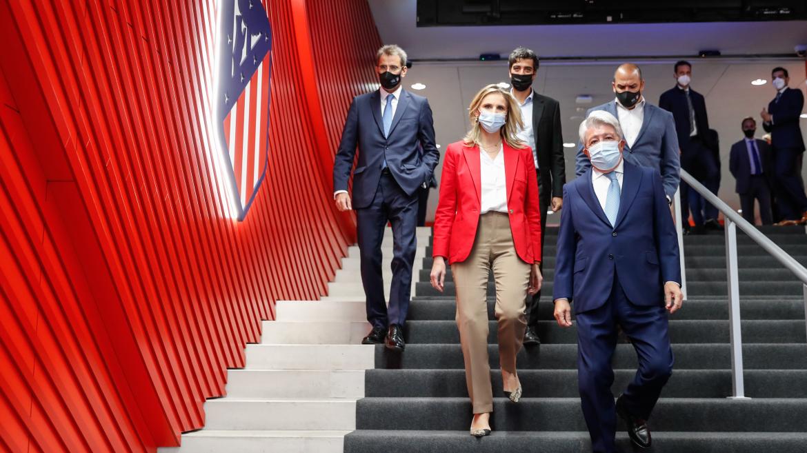 La consejera bajando las escaleras del Wanda Metropolitano junto al presidenta del club y el escudo del equipo de fondo