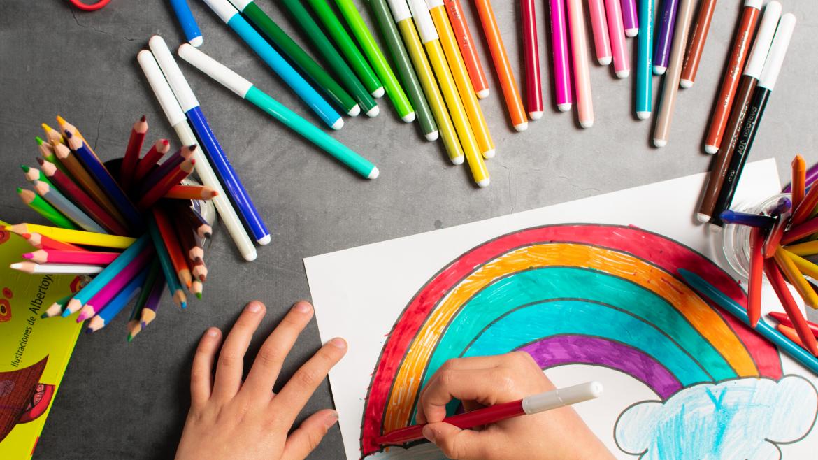 Las manos de un niño pintando un arcoiris