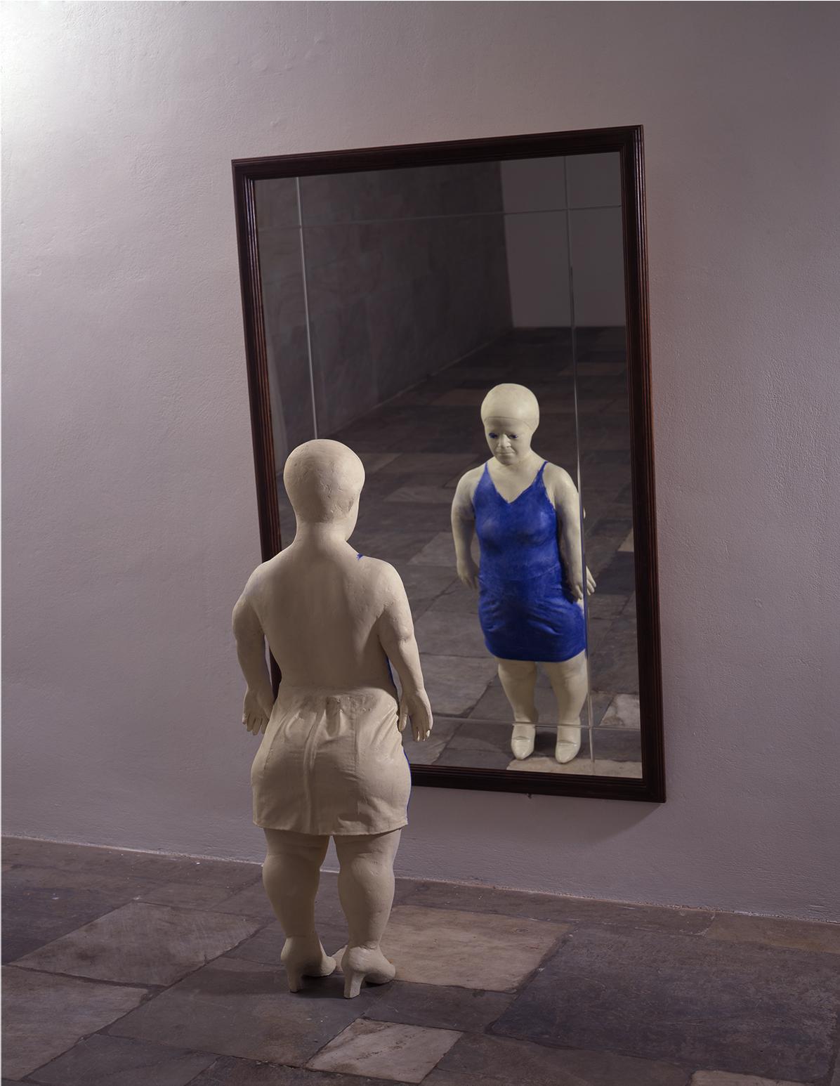 Gran espejo de pie de cuerpo entero y una mujer vestida se encuentra cerca  de él