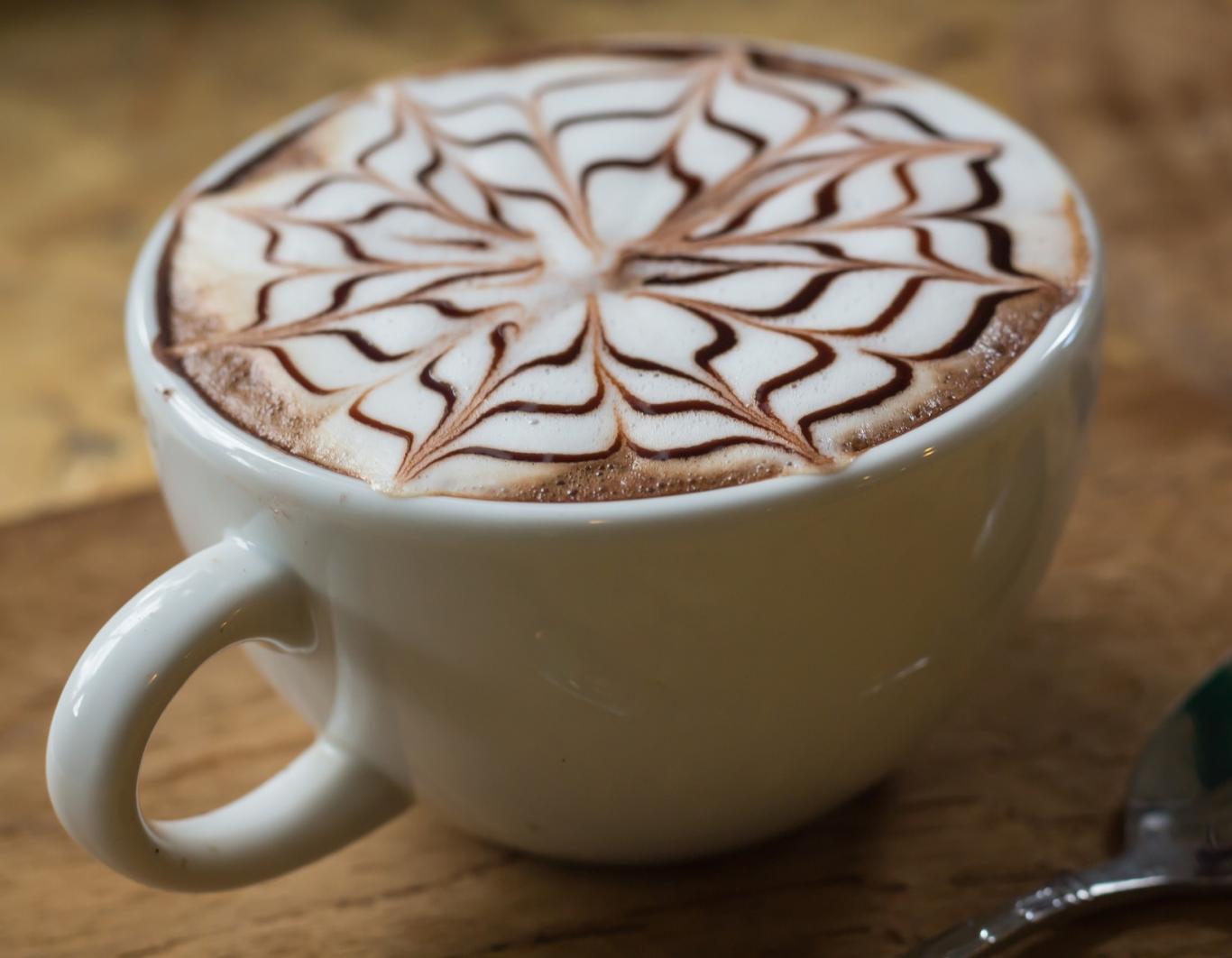 Imagen de una taza de café con espuma de leche decorada con un dibujo