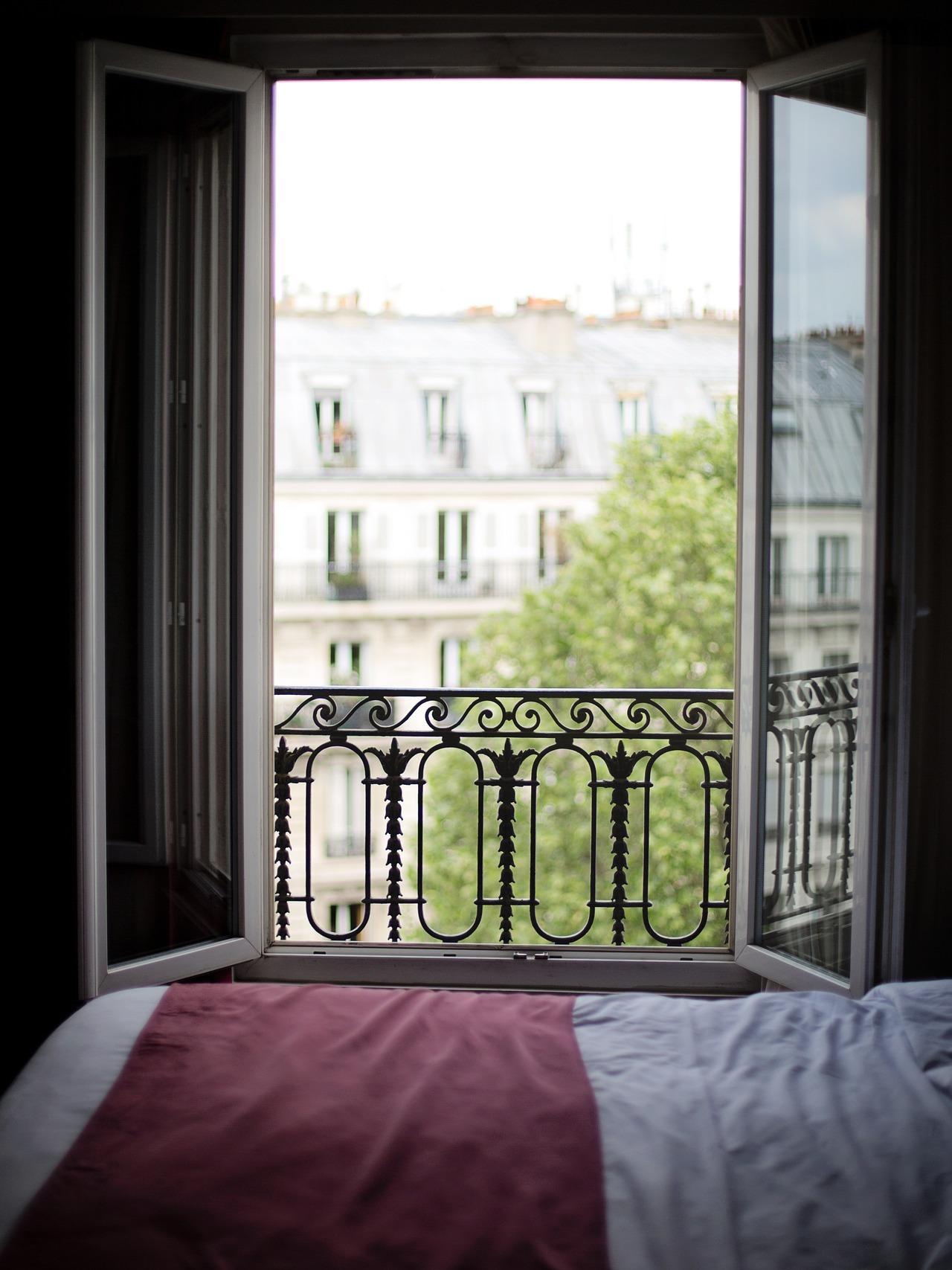 Imagen de la ventana abierta de un dormitorio en penumbra