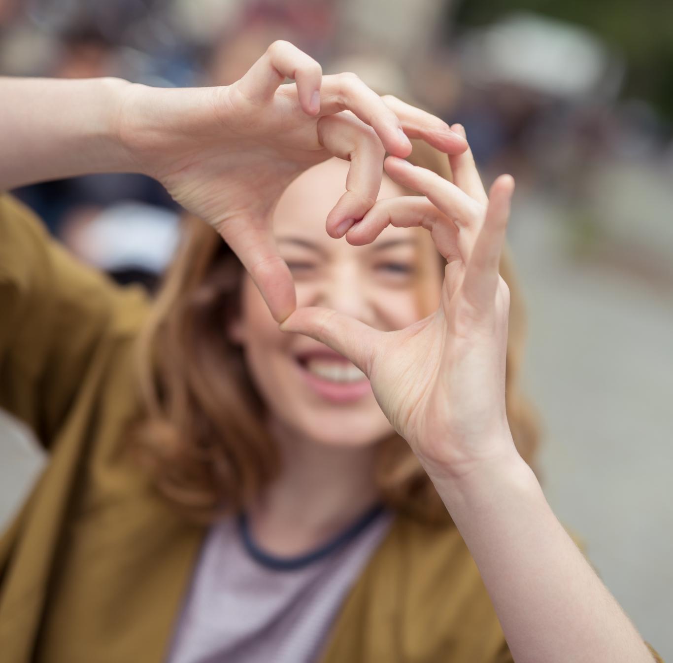 Una chica haciendo un la forma de un corazon con las manos