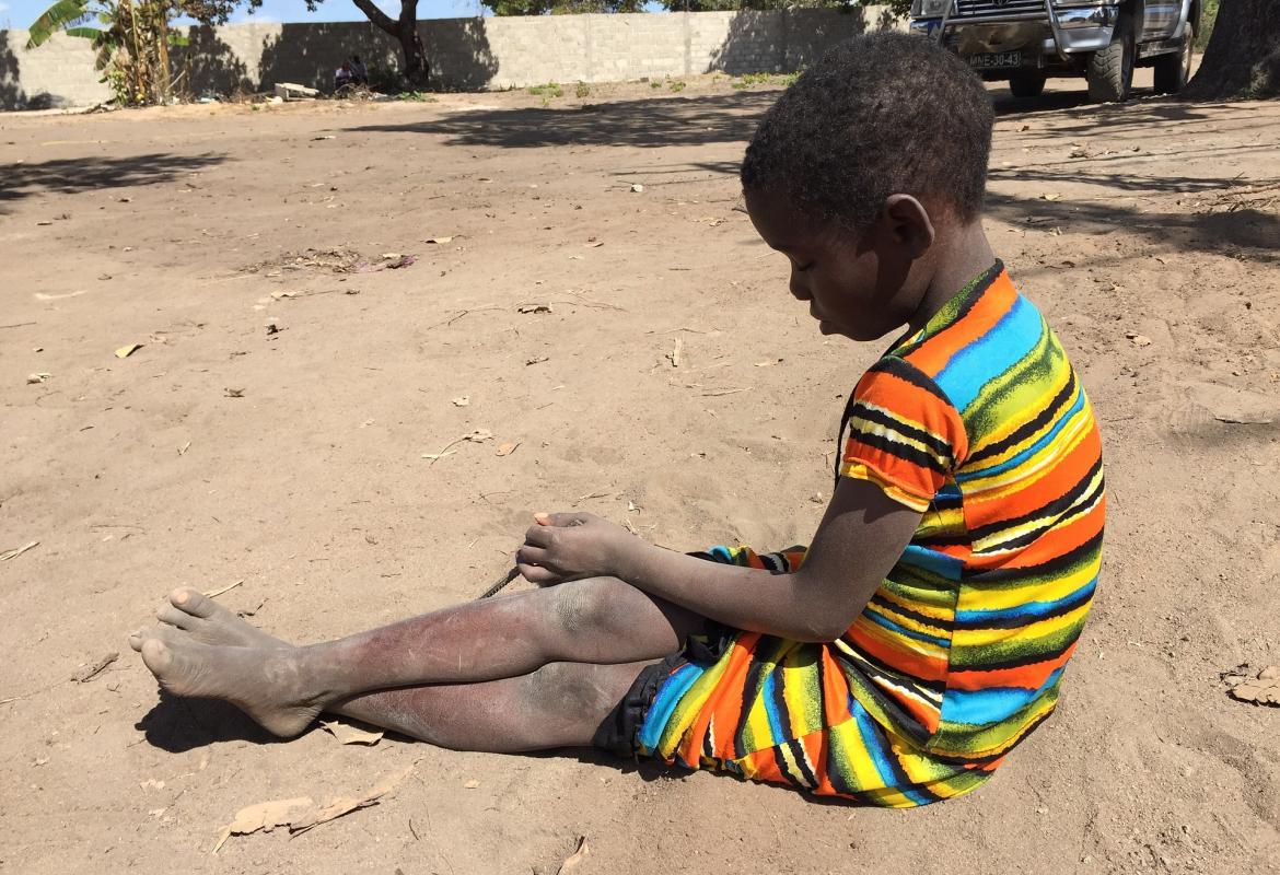 niña africana sentada en suelo de tierra