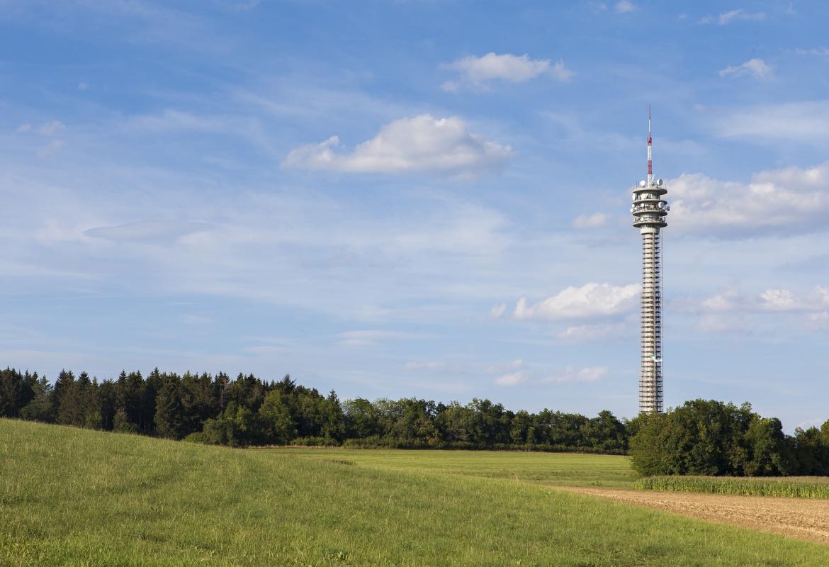 Antena de telefonía móvil alejada de la ciudad, tras un prado verde