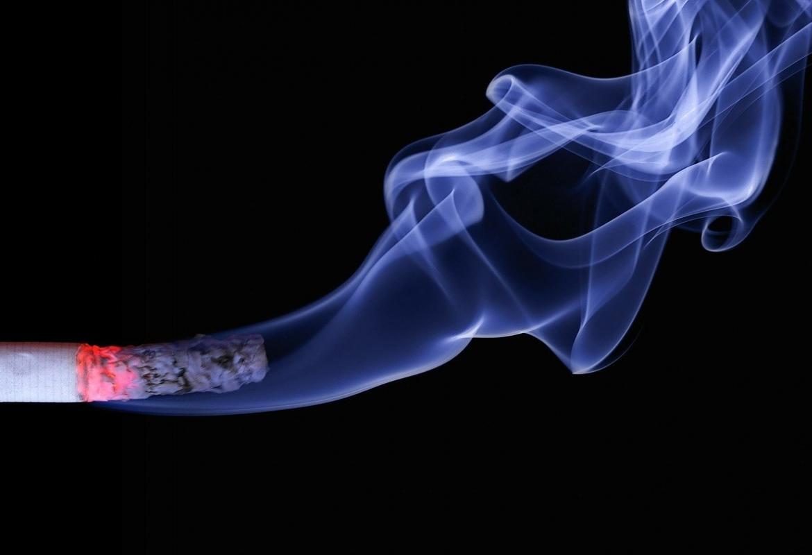 Humo de un cigarro encendido sobre fondo negro