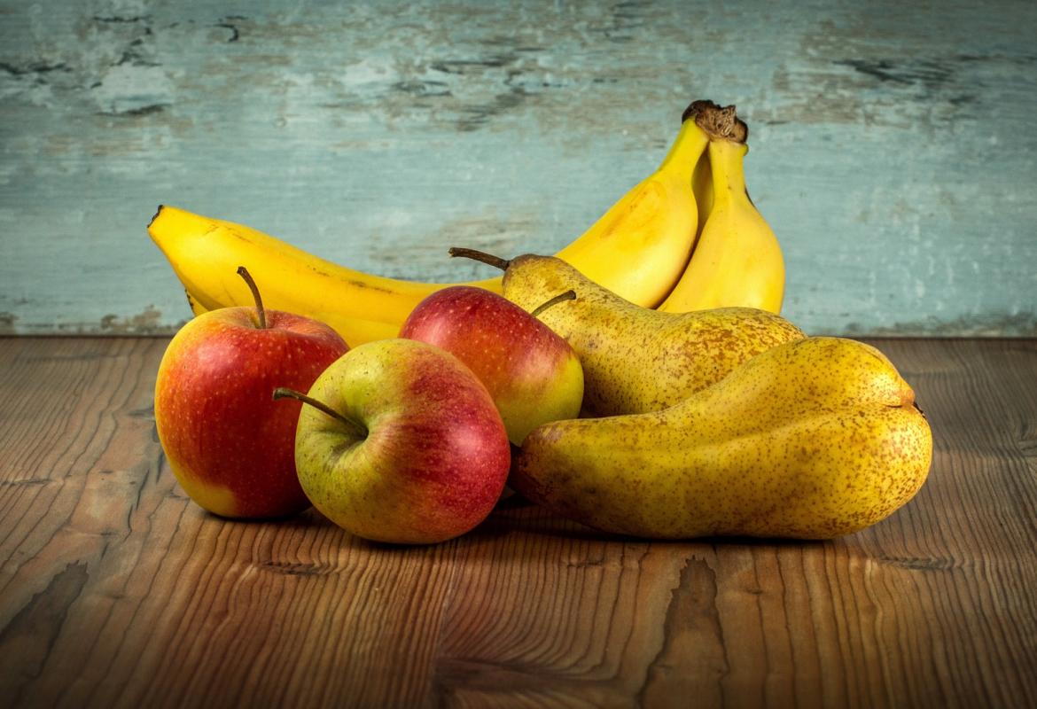 pera, plátano y manzanas sobre una mesa de madera