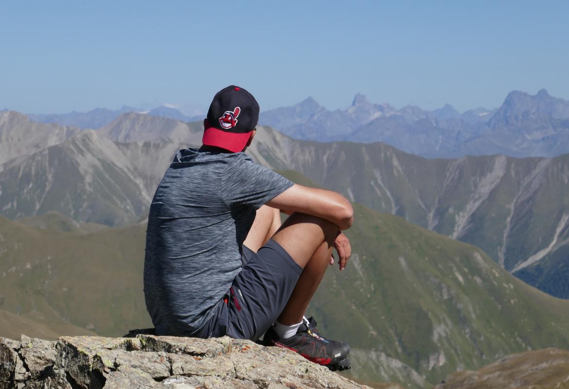 chico sentado en lo alto de la montaña 