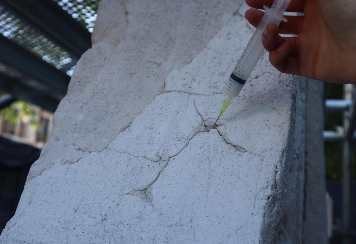 restorer injecting material with a needle into some cracks