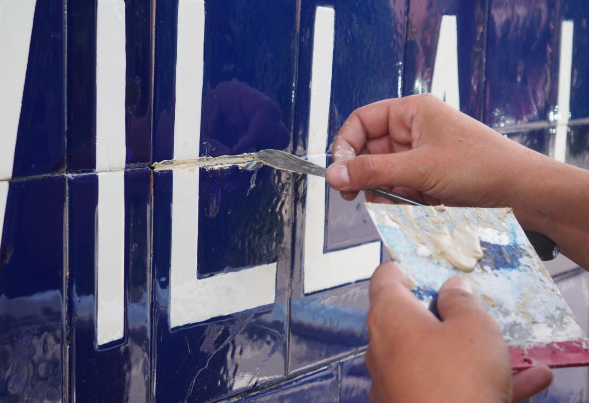 espátula sobre letras blancas y fondo azul de azulejos